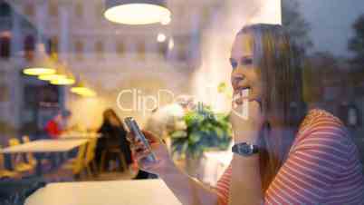 Happy woman in cafe thinking over sms she typing