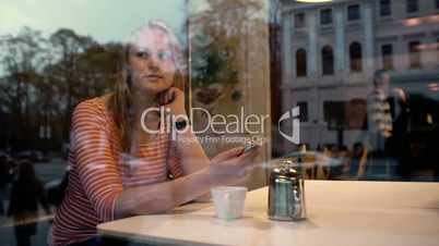 Woman with phone in cafe enjoying outside view