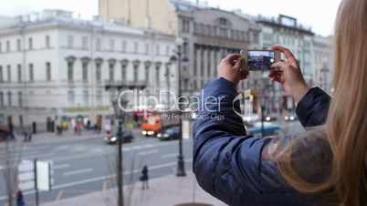 Woman with smartphone taking pictures of city
