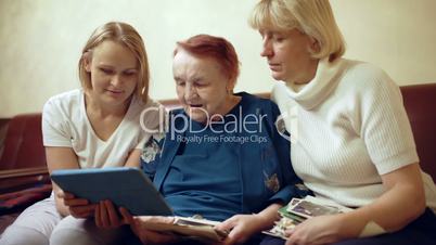 Family of three women looking photos on touchpad