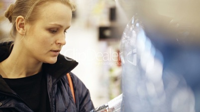 Woman taking a bottle of mineral water and putting it in the shopping basket