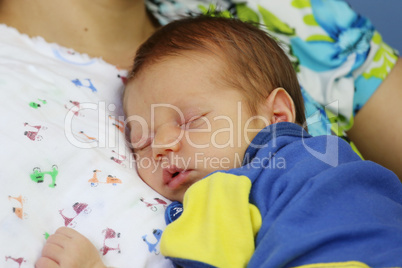 Newborn sleeping in the arms of his mother