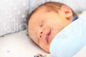 Blanket covering a newborn smiling.  Focus in the blanket.