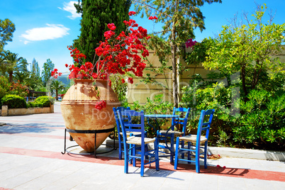 The amphora with flowers and traditional Greek table and chairs