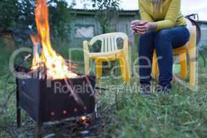 Woman with tea near the fire in the yard