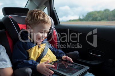 Happy boy playing with touchpad in the car
