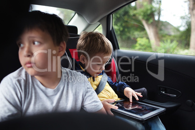 Two boys traveling on the back seat of a car