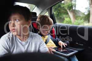 Two boys traveling on the back seat of a car