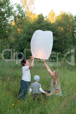 Family of three flying paper lantern outdoor