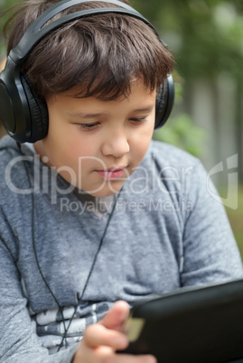 Teenager in headphones using pad outdoor