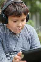 Teenager in headphones using pad outdoor