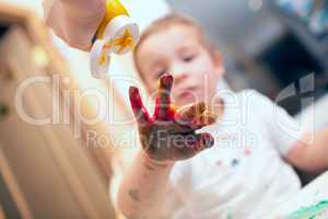Pressing finger-paint on boys hand