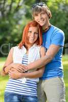 Romantic teenage couple hugging in sunny park