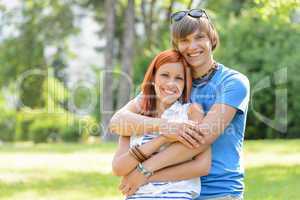 Teenage couple hugging in sunny park smiling