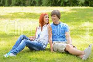 Teenage couple sitting grass looking each other