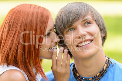 Teenage woman whispering to her boyfriend outdoors