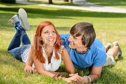 Teenage couple lying on grass laughing together