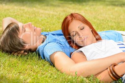 Teenage couple relaxing on grass closed eyes