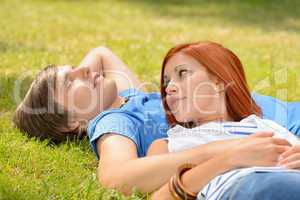 Romantic teenage couple lying on grass summer