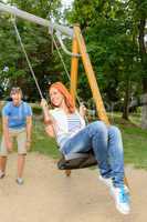 Playful teenage couple girl on swing