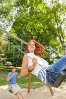 Two teenagers on swing playground in park
