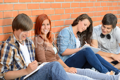 Students friends sitting in row outside college