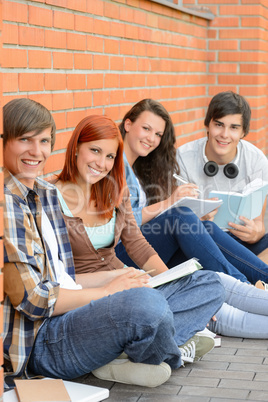 College students sitting outside by brick wall