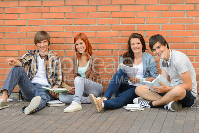 College students sitting ground by brick wall
