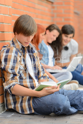 Young man studying book friends in background