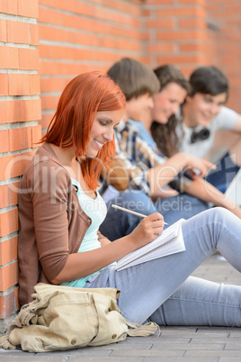 Studying girl writing notes friends sitting background