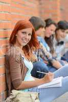 Student girl sitting outside campus with friends