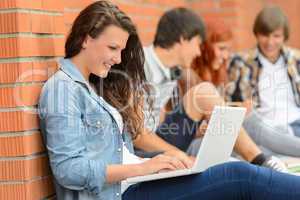 Student girl with laptop and friends outside
