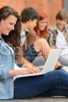 Young studying woman using laptop outside college