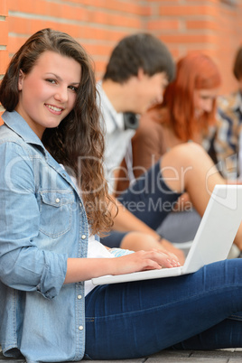 Girl working on laptop friends in background