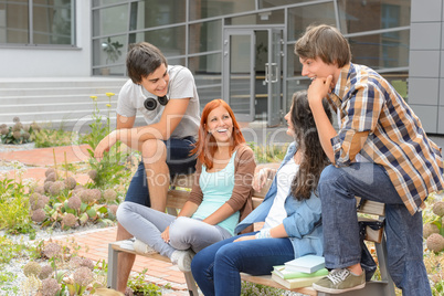 Student friends sitting outside campus laughing