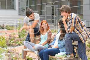 Student friends sitting outside campus laughing