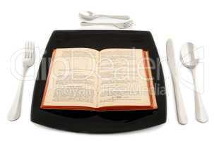 Metaphoric concept with physics book in the plate with cutlery