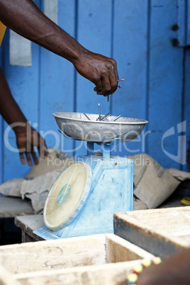 African carpenter weighs nails on a scale