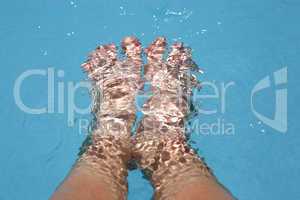 Splashing female feet in a swimming pool