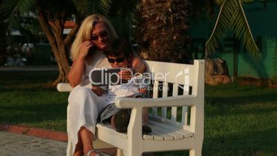 mother and son using digital tablet in park