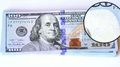 magnifying glass over a new 100 dolar bill