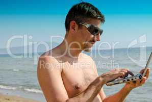 Man relaxing on the Beach with his Notebook