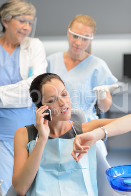 Impatient woman patient on phone at dental clinic