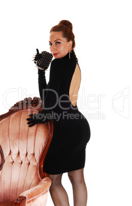 Woman standing on armchair.