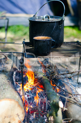 Tourist boiler with food and a mug with water on a fire