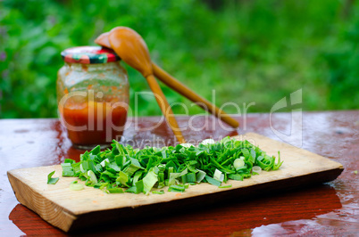 Chopped green onions on a cutting Board, on the background of tw