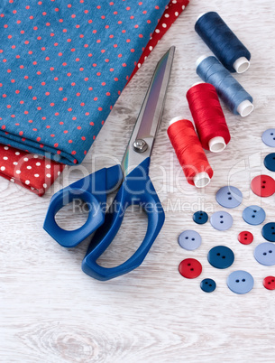 scissors, threads, fabric and buttons on wooden table