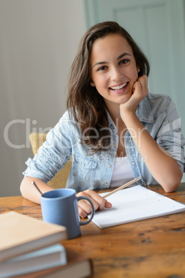 Teenage student girl studying at home smiling