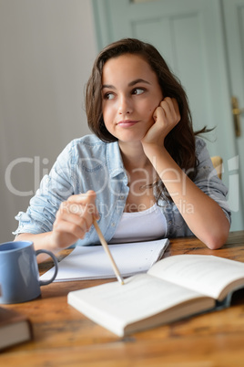 Bored teenage student girl studying at home