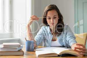 Teenage girl studying reading book at home
